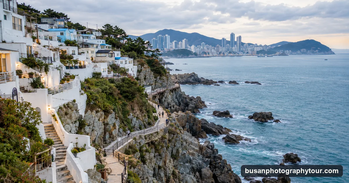 A white cliffside village with narrow lanes above a blue sea and a coastal walking path in Busan